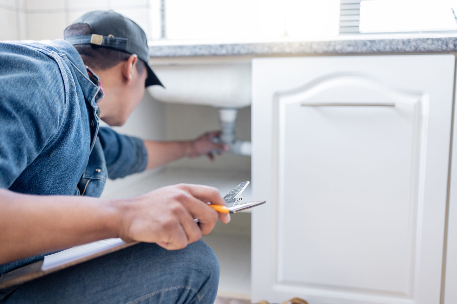 Home inspector checking plumbing under a sink